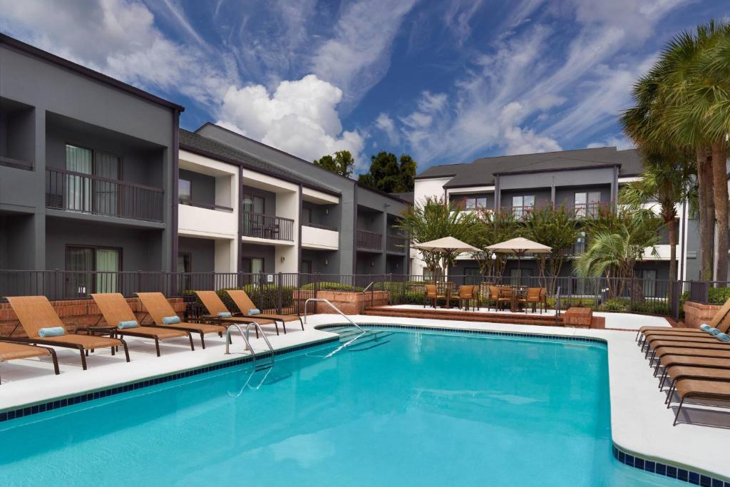 a swimming pool in front of a building with chairs at Courtyard by Marriott Tallahassee Downtown/Capital in Tallahassee