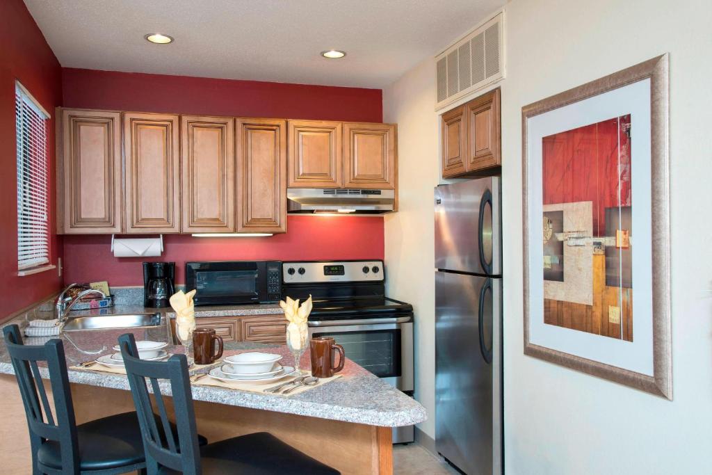 uma cozinha com armários de madeira e um frigorífico de aço inoxidável em Residence Inn Kalamazoo East em Kalamazoo