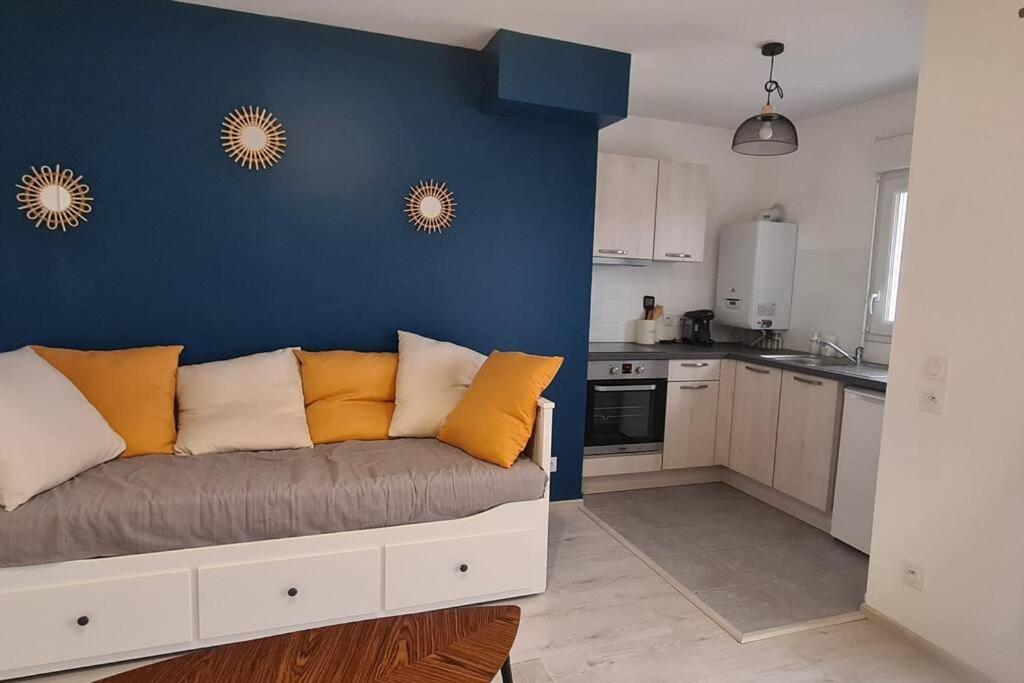 salon z kanapą przy niebieskiej ścianie w obiekcie Superbe studio en résidence neuve w mieście Chapelle-Saint-Mesmin