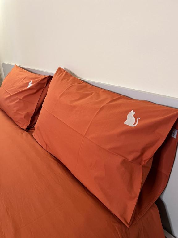 a bed with an orange pillow with an apple logo on it at Il Cantuccio di Gioia in Brescia