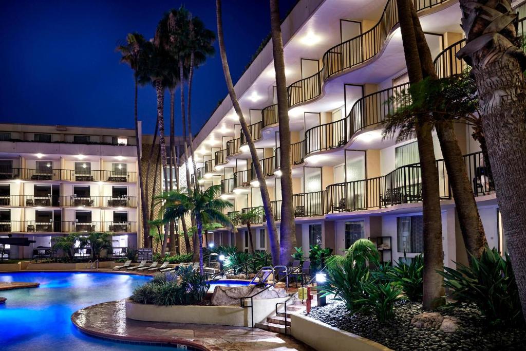 a hotel with a pool and palm trees at night at Los Angeles Airport Marriott in Los Angeles