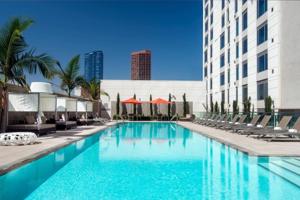 uma piscina com espreguiçadeiras e um edifício em Courtyard by Marriott Los Angeles L.A. LIVE em Los Angeles