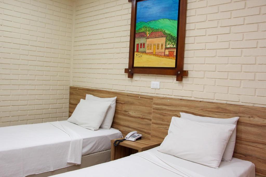 Habitación con 2 camas y espejo en la pared. en Rede Andrade Goiania Centro, en Goiânia