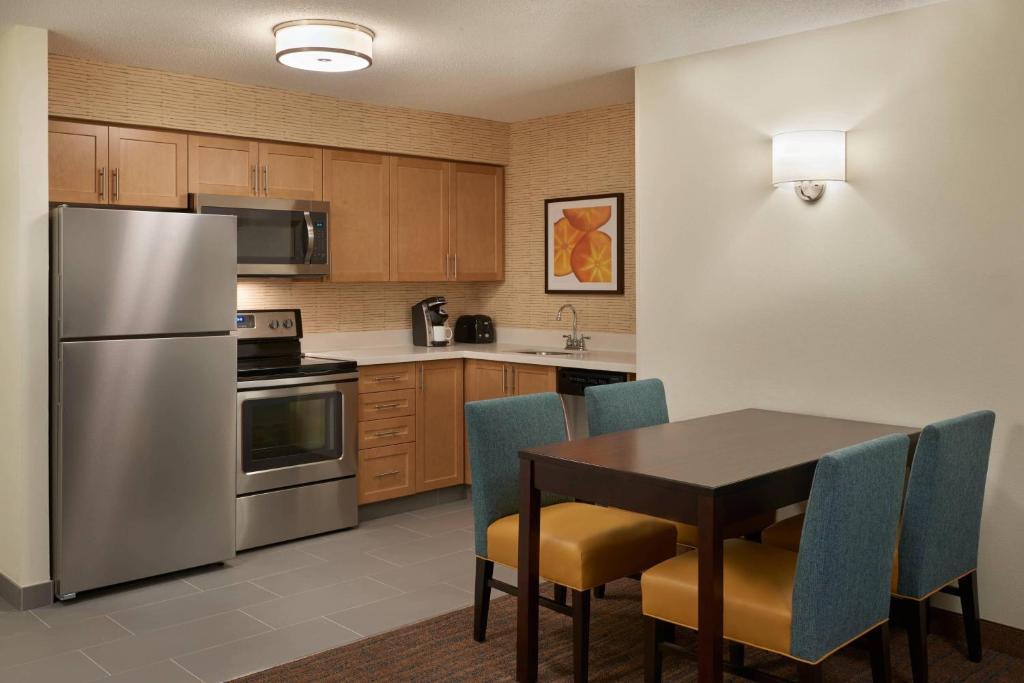 eine Küche mit einem Tisch und einem Kühlschrank aus Edelstahl in der Unterkunft Residence Inn by Marriott Toronto Airport in Toronto