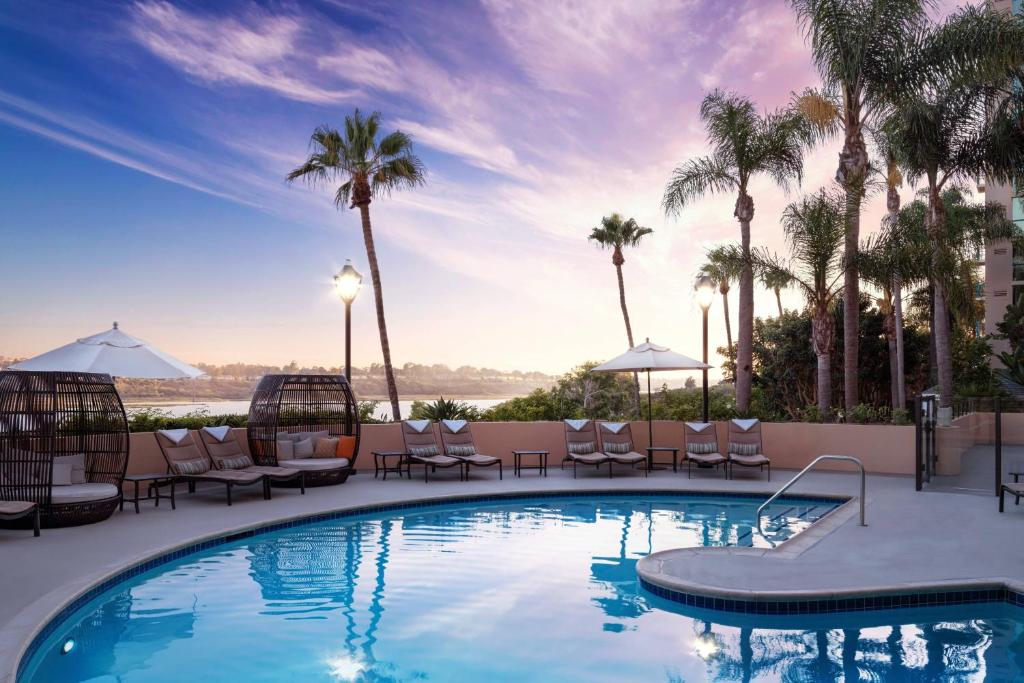 a swimming pool with chairs and palm trees at Newport Beach Marriott Bayview in Newport Beach