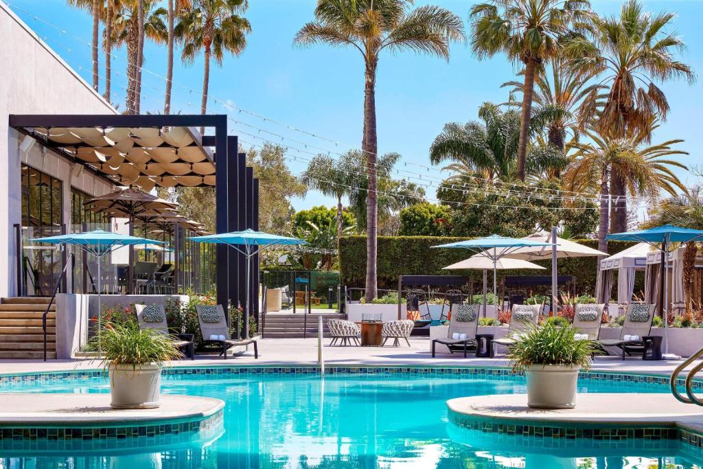 una piscina con sillas, sombrillas y palmeras en Torrance Marriott Redondo Beach, en Torrance