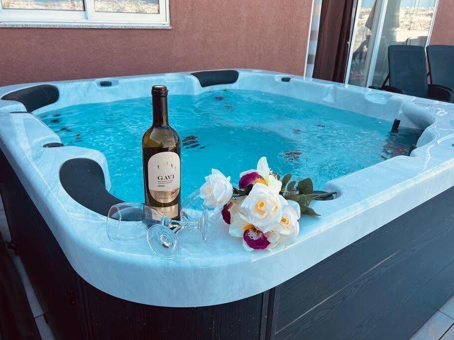 uma garrafa de vinho e flores numa banheira de hidromassagem em The Hazel penthouse with private jacuzzi em Birkirkara