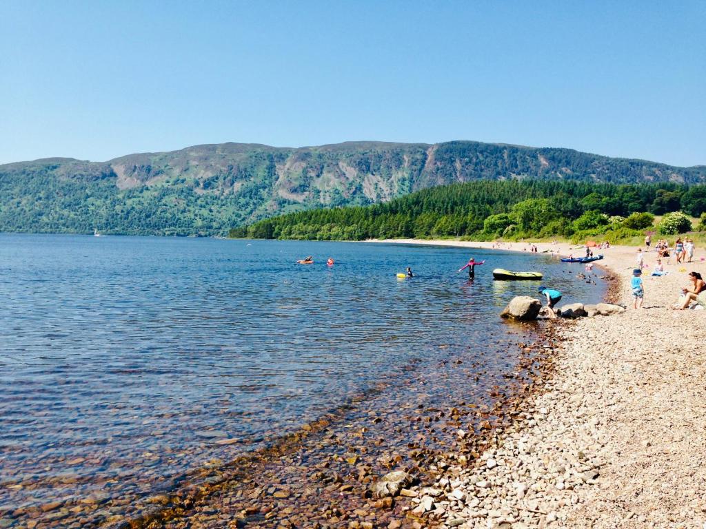 un grupo de personas en una playa en el agua en 1 Loch Ness Heights en Inverness