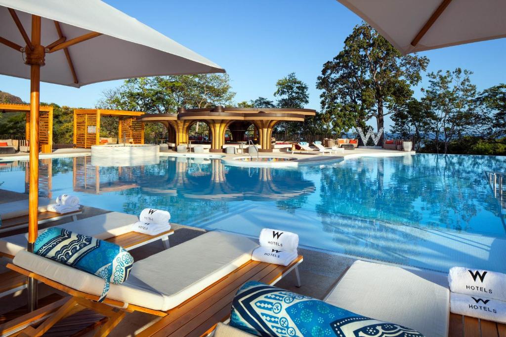 a swimming pool with chairs and an umbrella at W Costa Rica Resort – Playa Conchal in Playa Conchal