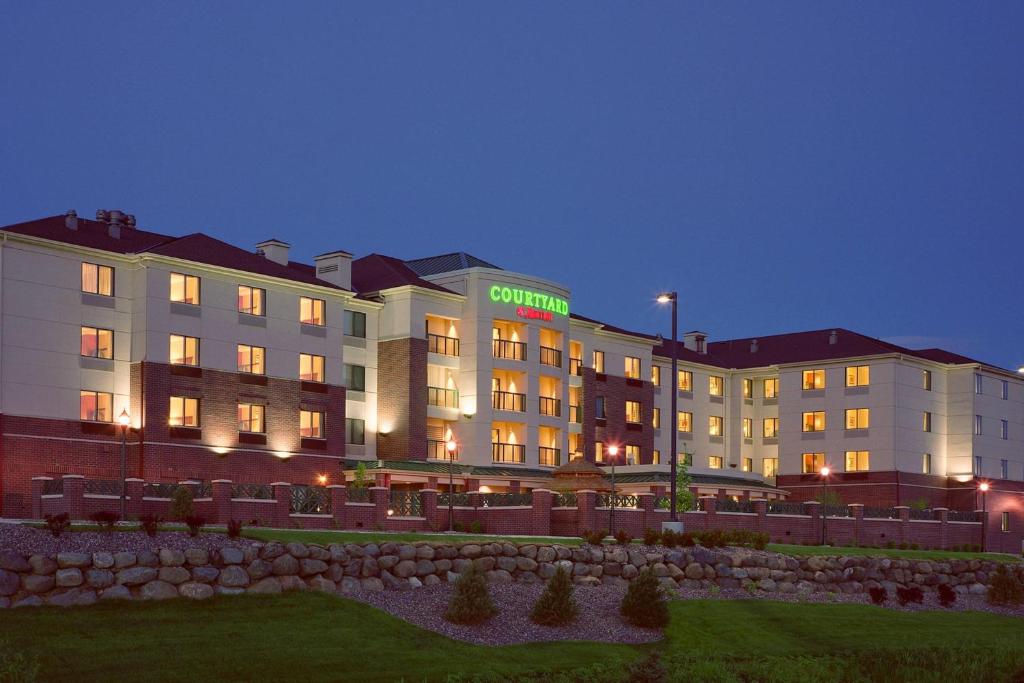 a hotel building with a green sign on it at night at Courtyard by Marriott Madison East in Madison
