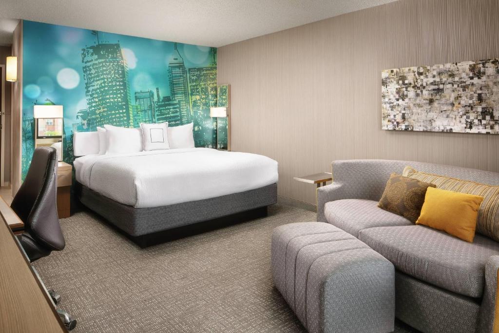 a hotel room with a bed and a couch at Courtyard Indianapolis at the Capitol in Indianapolis