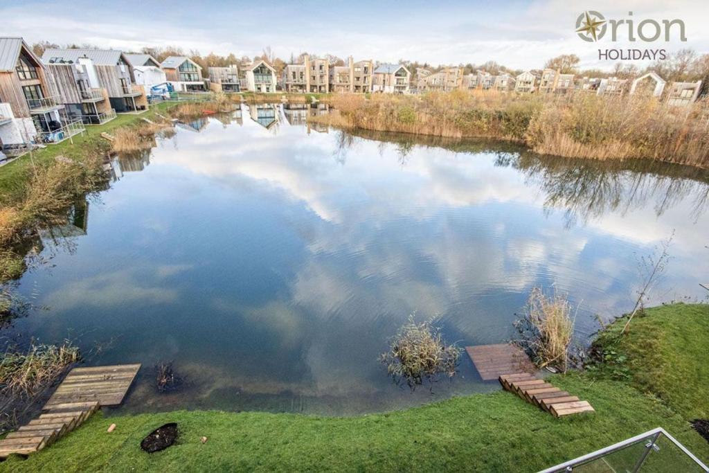 a large body of water with buildings in the background at Minety Lake 43, Green Haven in Somerford Keynes