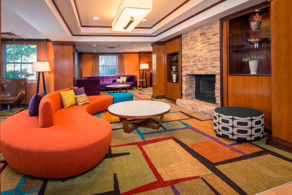 a lobby with an orange chair and a fireplace at Fairfield Inn & Suites by Marriott Williamsburg in Williamsburg