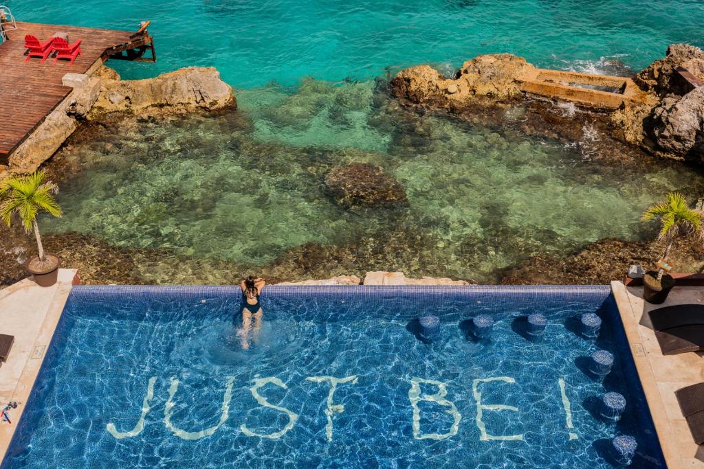 a woman standing in a swimming pool with the words just be at Hotel B Cozumel in Cozumel