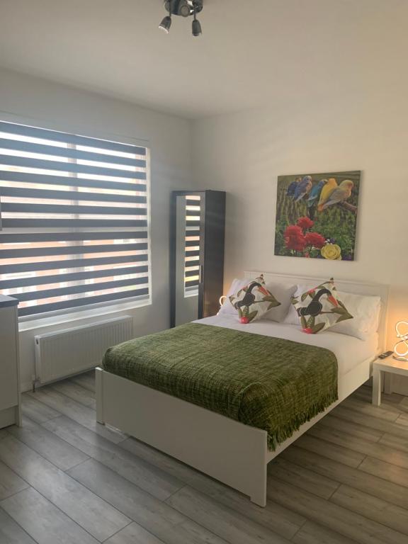 a bedroom with a large bed with a green blanket at Bloomsbury House - Modern studios near Anfield in Liverpool