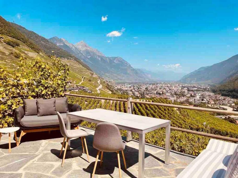 a table and chairs on a balcony with a view at Magnifique Mazot Dans Les Vignes in Martigny-Combe