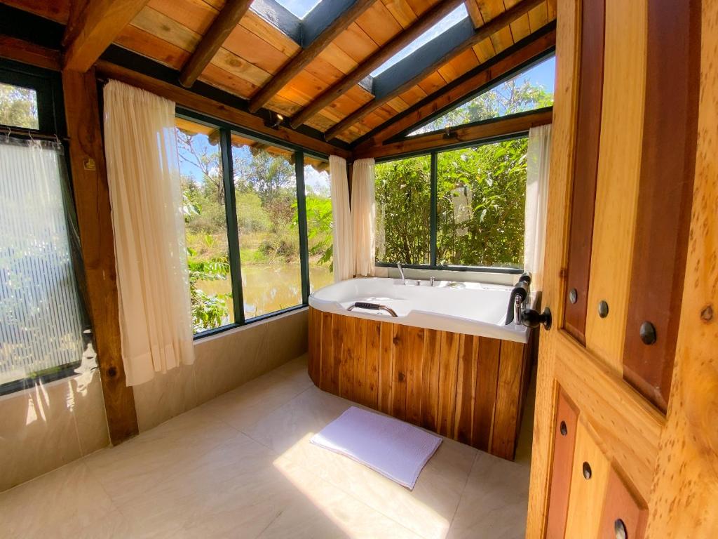 Habitación con ventanas y baño con bañera. en Suite Cabaña Cantodeagua-Jacuzzi, en Villa de Leyva