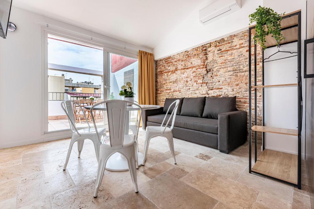 a living room with a table and chairs and a brick wall at Gran Atico duplex con Barbacoa y Terraza en Barri Port Maritim in Tarragona