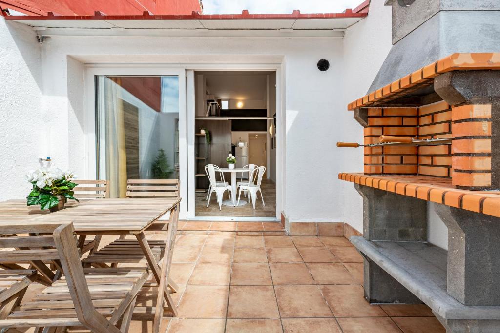 a patio with a table and chairs and a fireplace at Atico duplex con Barbacoa y Terraza en Barri Port Maritim in Tarragona