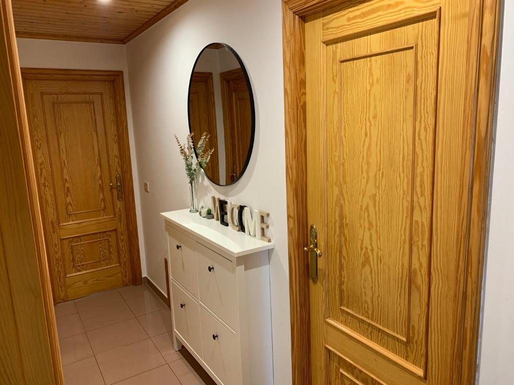 La salle de bains est pourvue d'un miroir, d'une coiffeuse blanche et d'une porte. dans l'établissement Apartamento vacacional en O Grove, à O Grove