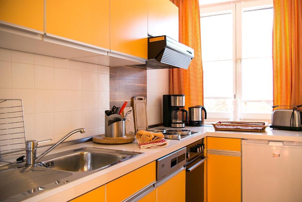 een keuken met oranje kasten en een wastafel bij Ferienwohnung Edelweiss in Füssen
