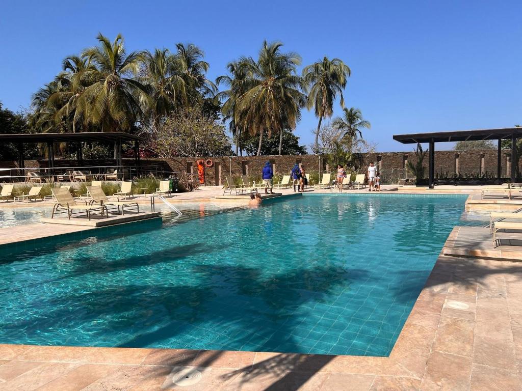 a large blue swimming pool with palm trees in the background at Espectacular Loft para estrenar, Reserva del Mar, playa salguero in Gaira