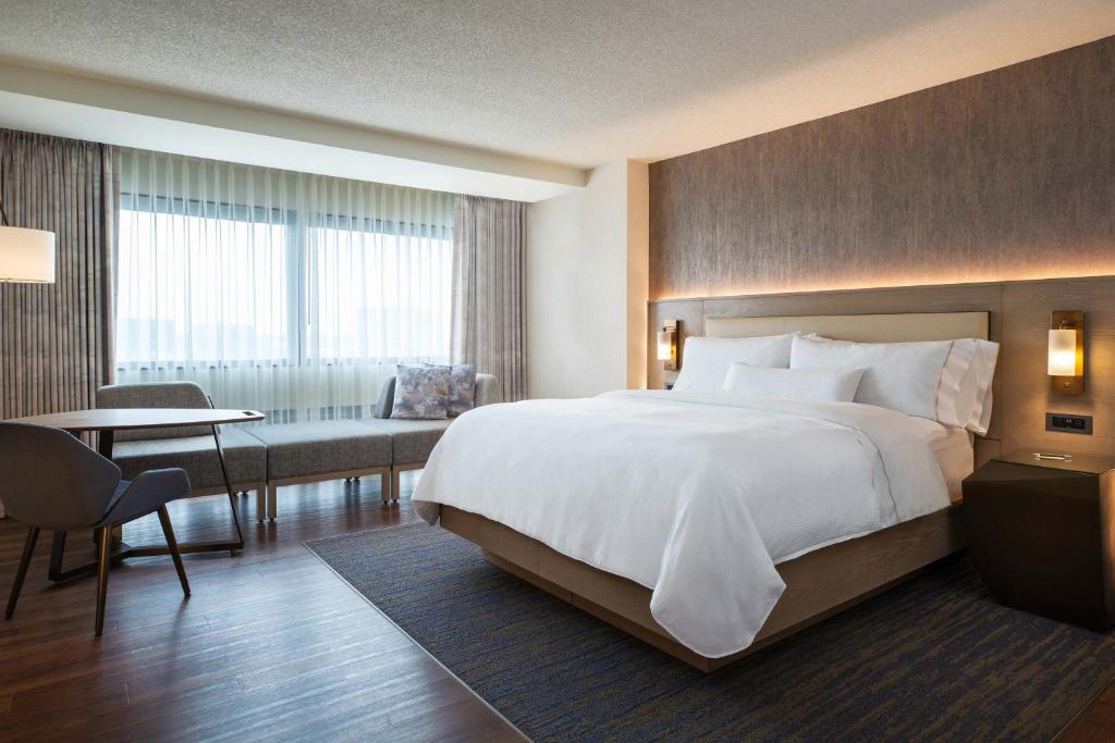 a hotel room with a large bed and a table at The Westin O'Hare in Rosemont