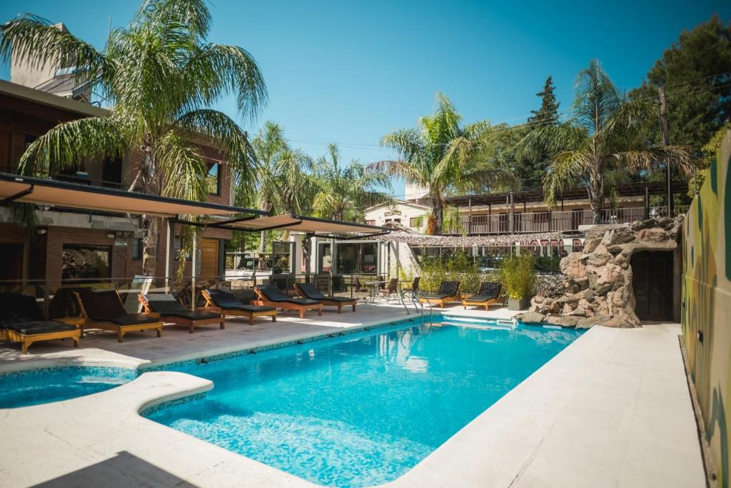 a pool at a resort with chairs and trees at Altos del Champaqui in Villa Carlos Paz