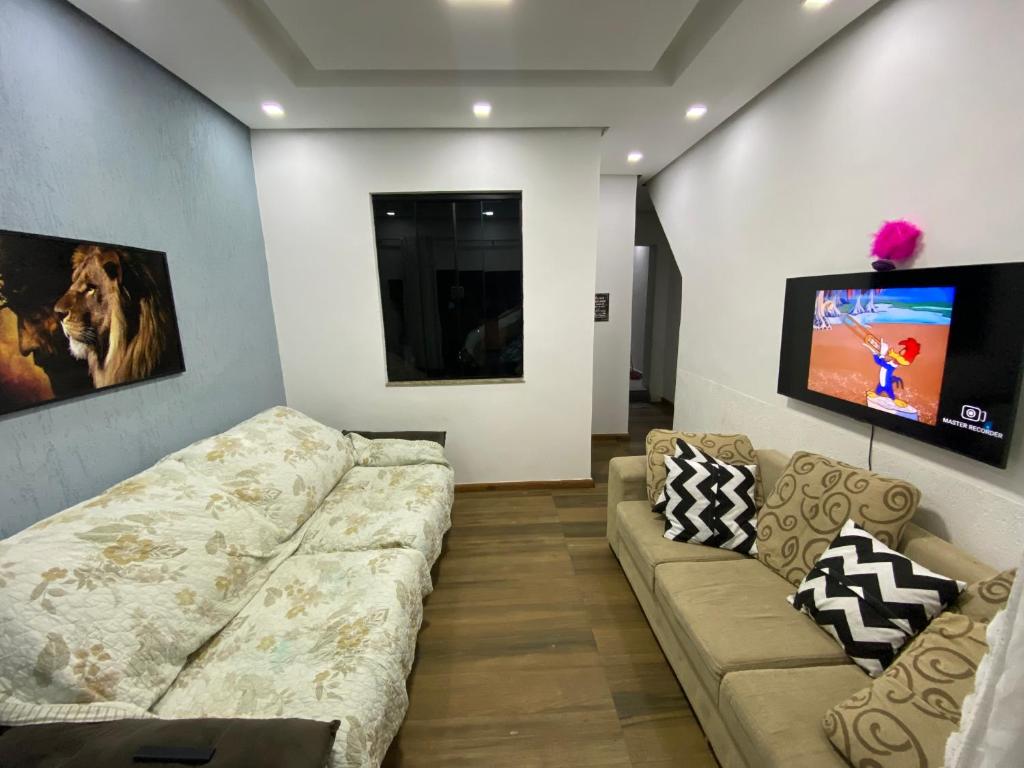 uma sala de estar com um sofá e uma televisão de ecrã plano em valenshostel em Angra dos Reis