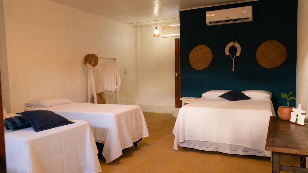 een kamer met 2 bedden en witte tafels bij Manoah Trancoso in Trancoso