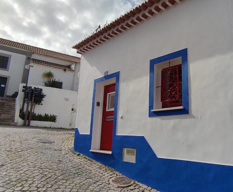 een wit en blauw huis met een rode deur bij Casa14 in Odeceixe