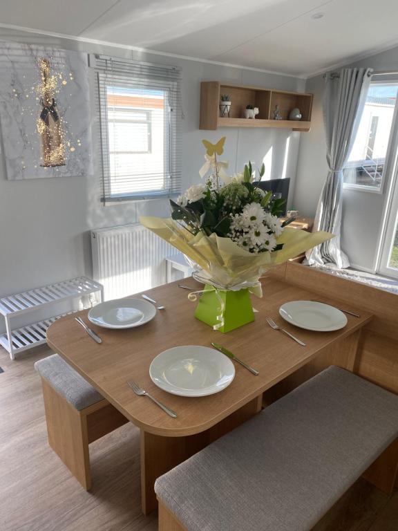 a dining room table with plates and flowers on it at Stylish 3 Bedroom caravan near the Beach in Walton-on-the-Naze