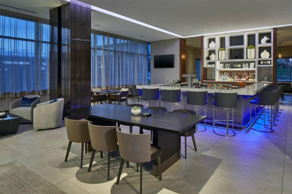 a dining room with a table and chairs and a bar at AC Hotel by Marriott Atlanta Airport Gateway in Atlanta