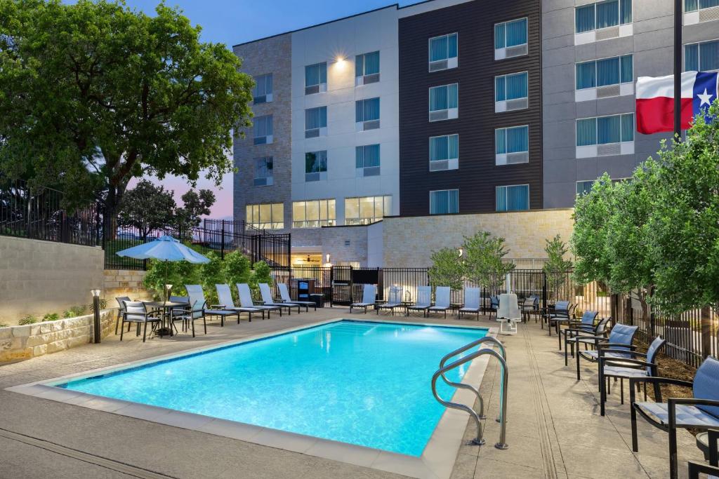 a swimming pool with chairs and tables and a building at TownePlace Suites by Marriott Austin Northwest The Domain Area in Austin
