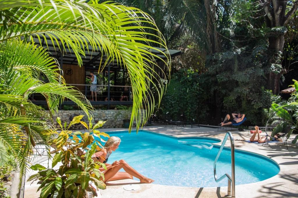 a swimming pool with two people in a resort at Believe Surf & Yoga Lodge Santa Teresa in Santa Teresa Beach