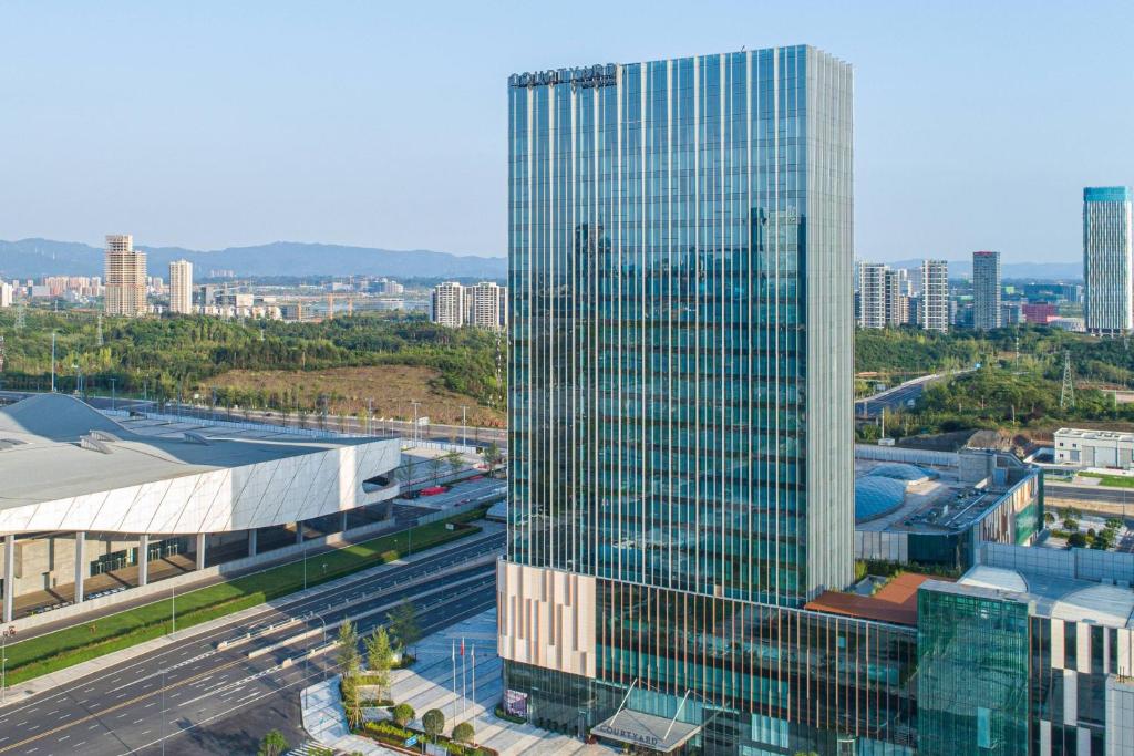 成都市にあるCourtyard by Marriott Chengdu Southの駅隣の高いガラス張りの建物