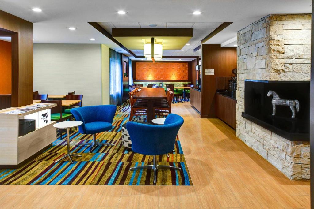 a lobby with blue chairs and a stone fireplace at Fairfield Inn and Suites by Marriott Atlanta Suwanee in Suwanee