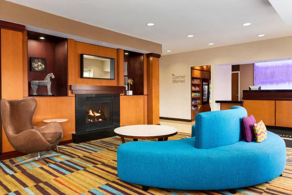 a living room with a blue chair and a fireplace at Fairfield Inn & Suites by Marriott Toledo Maumee in Maumee