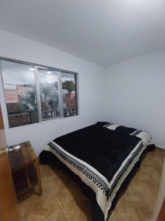 a bed in a room with two windows at Los balcones l in Medellín
