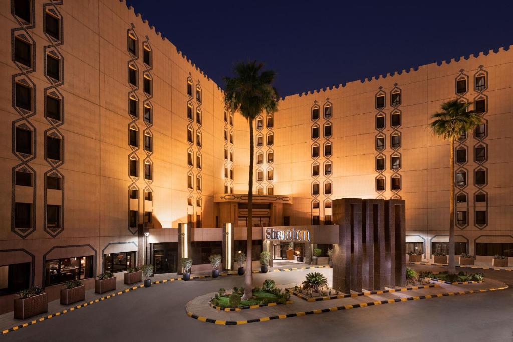 un grand bâtiment avec un palmier en face dans l'établissement Sheraton Riyadh Hotel & Towers, à Riyad