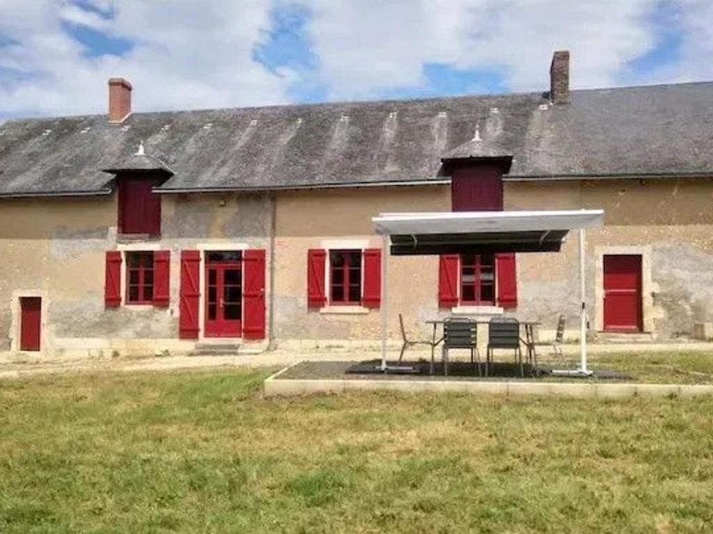 a building with red doors and a bench in front of it at Maison calme avec grand jardin en Berry, proche Châteauroux - FR-1-591-372 in Arthon