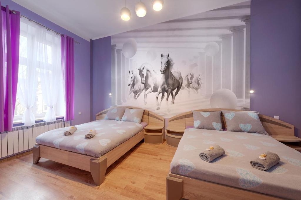 sypialnia z dwoma łóżkami i malowidłem ściennym koni w obiekcie Queen Apartments w Krakowie