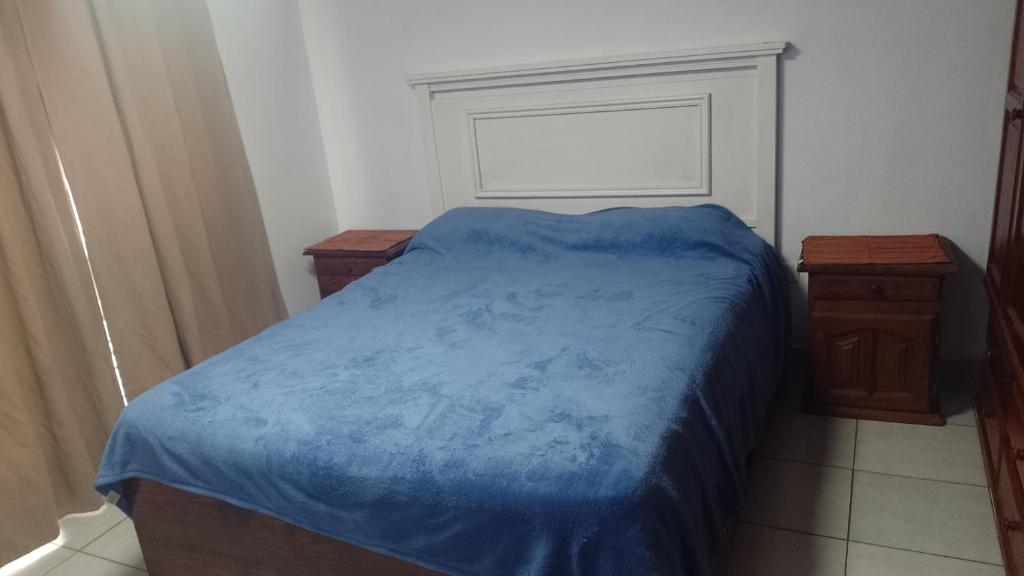 1 dormitorio con 1 cama azul y 2 mesitas de noche en Departamento el estadio en Santiago del Estero