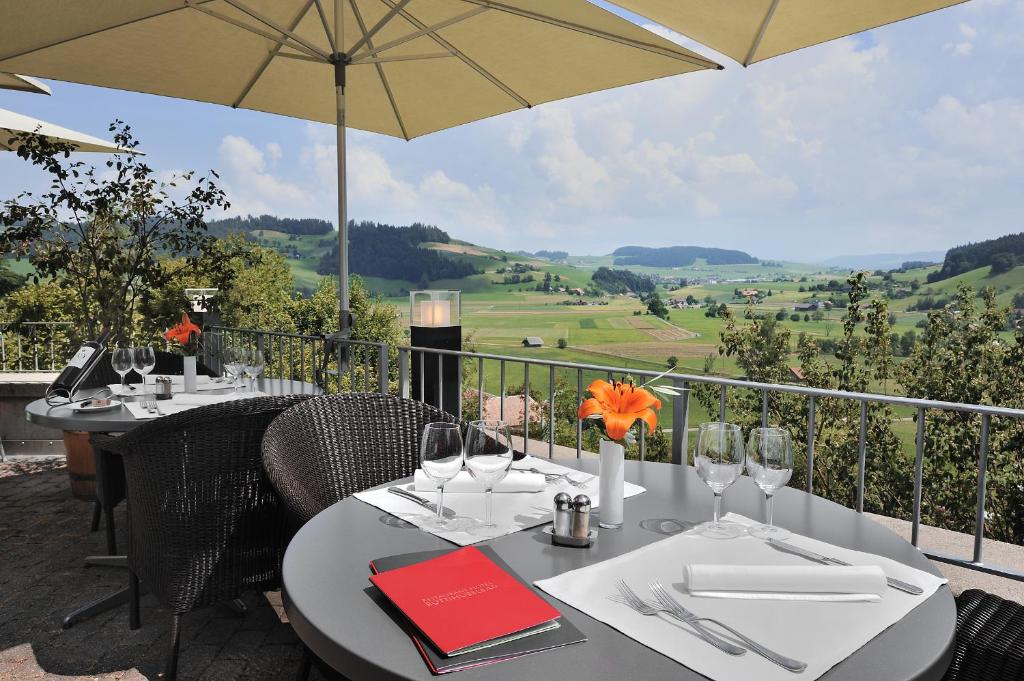 a table with wine glasses and an umbrella on a balcony at Restaurant Hotel Rüttihubelbad in Walkringen