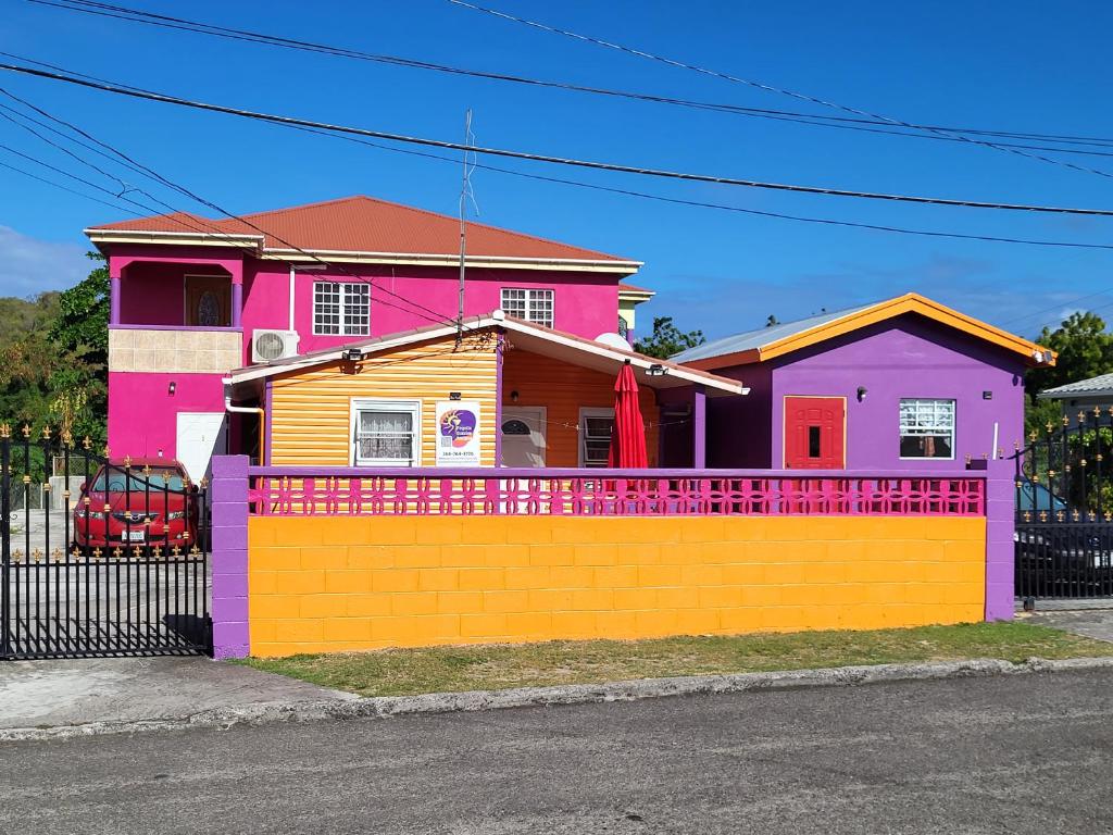 ein farbenfrohes Haus mit einem Zaun davor in der Unterkunft Tequila Sunrise Antigua in Osbourn