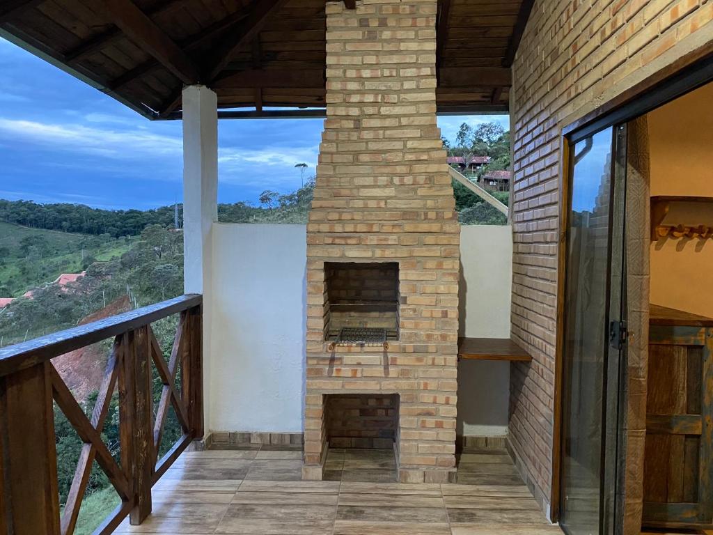 a brick fireplace in a house with a view at Ibitisuítes chalé in Lima Duarte