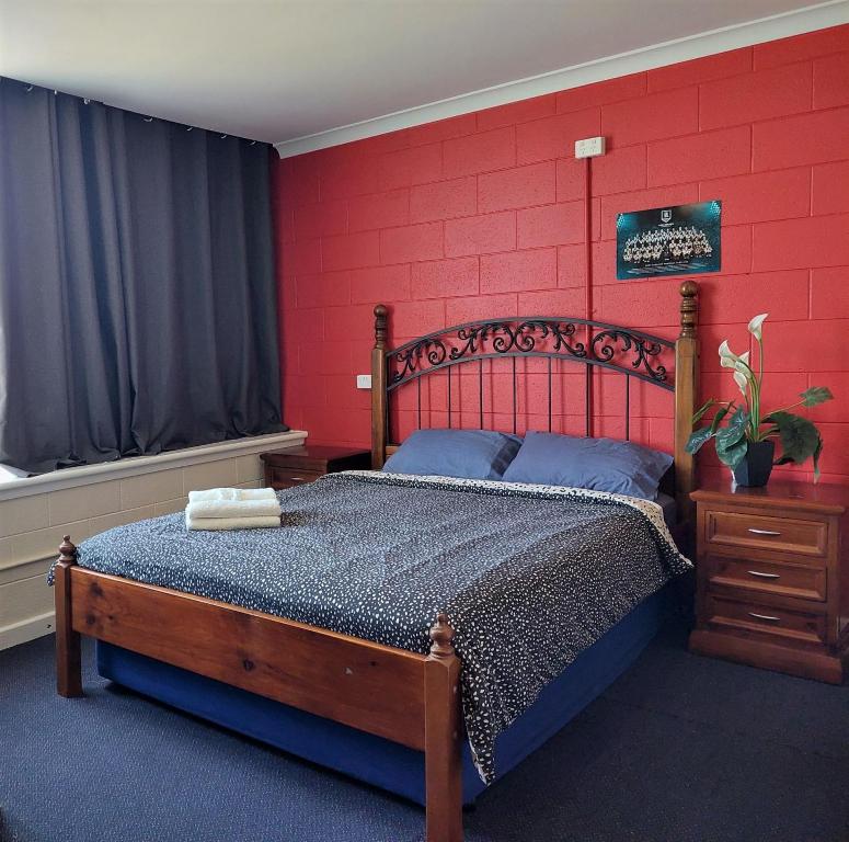 1 dormitorio con 1 cama con pared roja en Port Adelaide Backpackers, en Adelaida