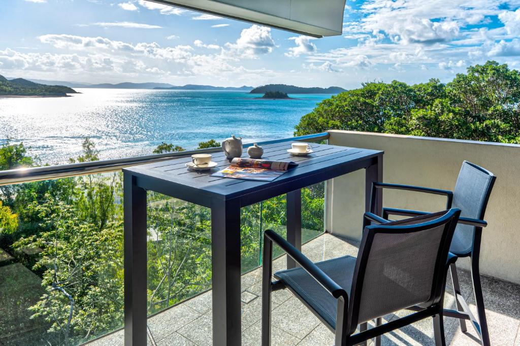 una mesa azul y sillas en un balcón con vistas al océano en Waves 6 on Hamilton Island by HIHA en Isla Hamilton