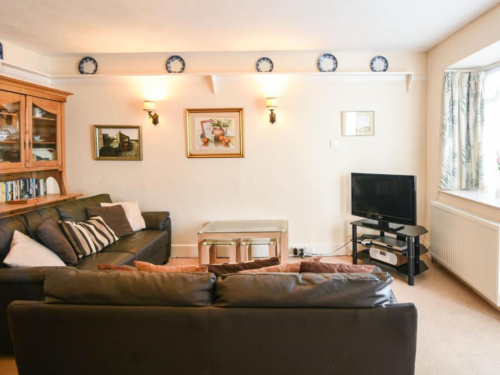 een woonkamer met een bank en een tv bij Okanagan in Lyme Regis