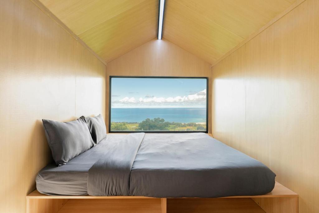 un letto in una piccola stanza con una grande finestra di Bobocabin Umarato, Sumba a Waikabubak